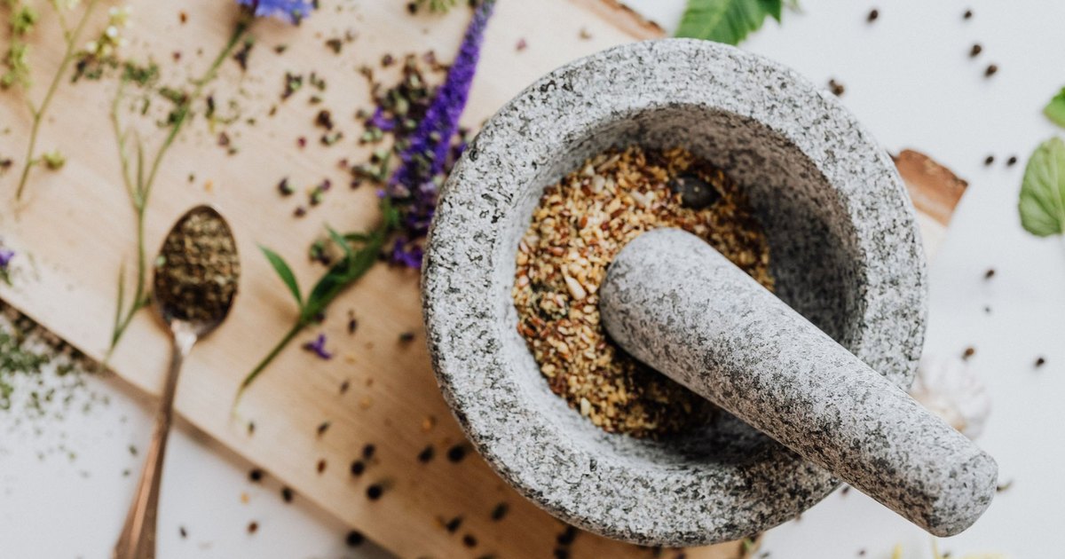 Dried herbs in a mortar and pestle on a wooden board