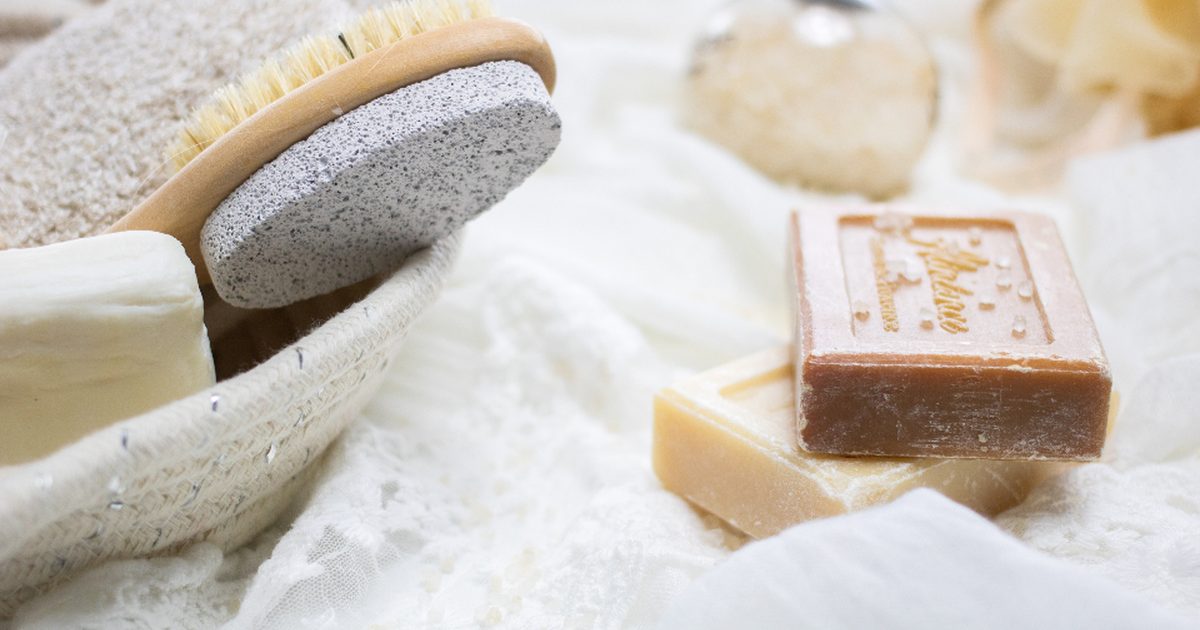 Bars of natural soap with a bath brush on white linen
