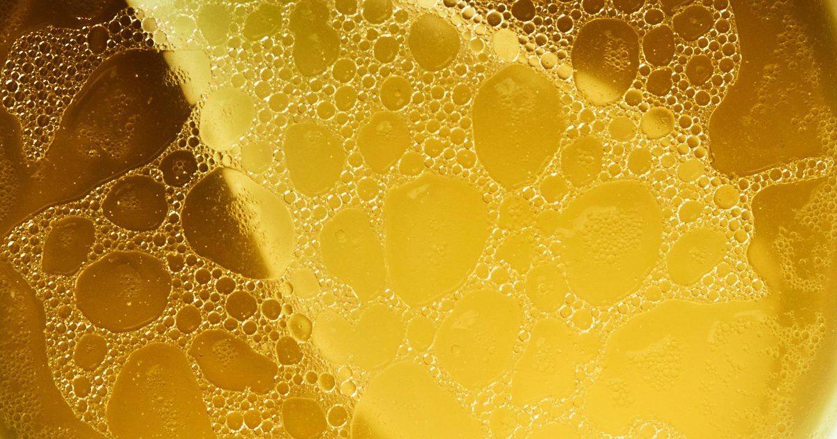 Close up of rich golden broth with a layer of fat on the surface