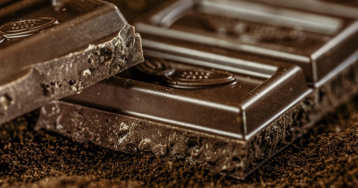 Squares of dark chocolate resting on cocoa powder