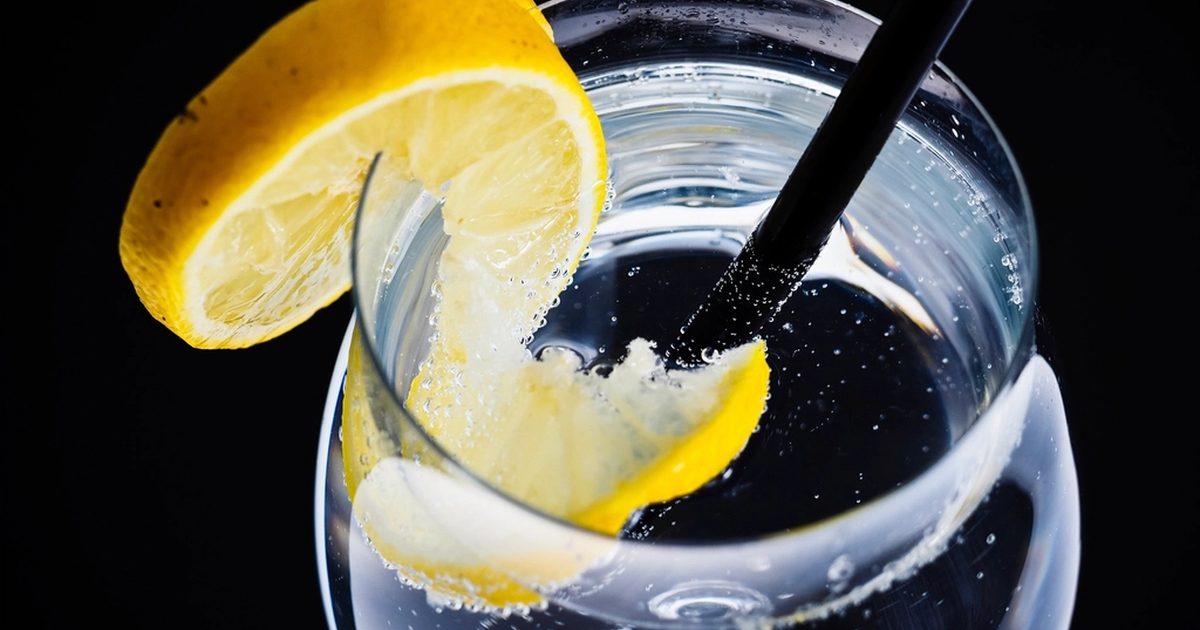 A glass of sparkling water with a lemon slice and a straw