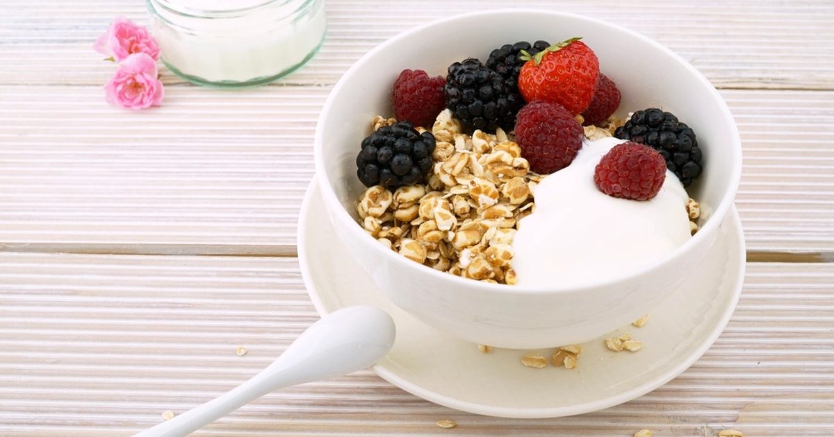 A bowl of yoghurt topped with granola and fresh berries