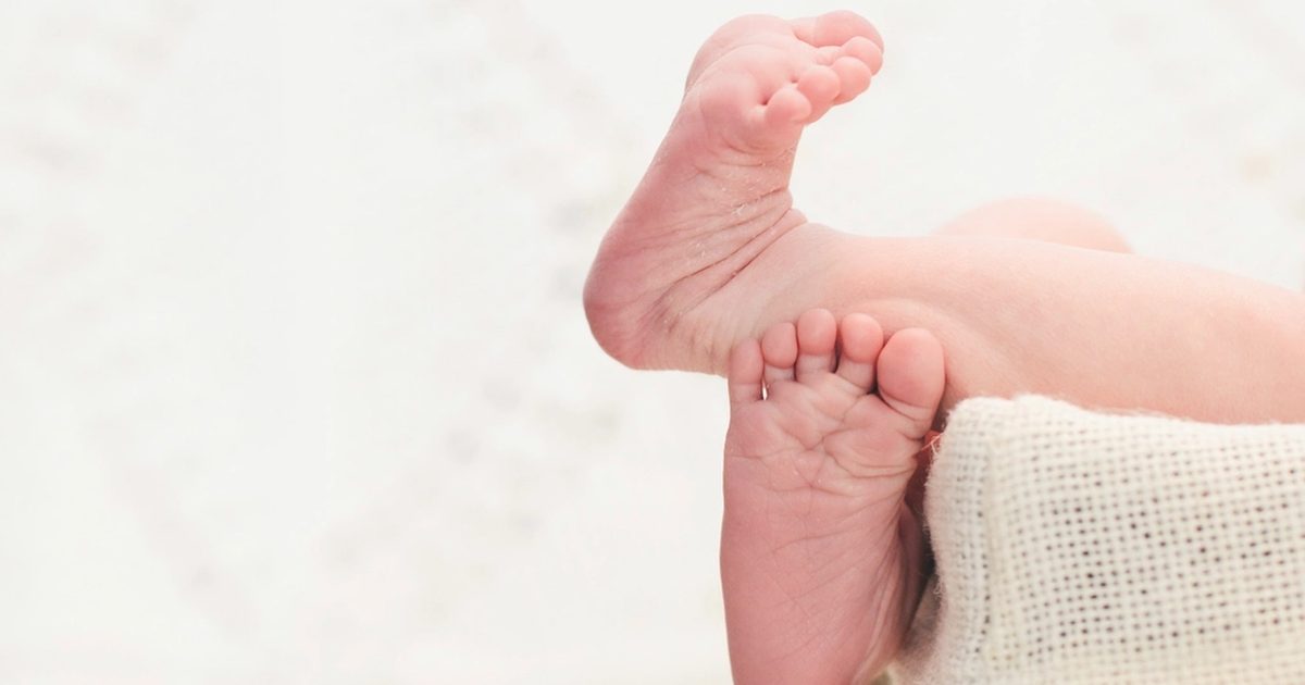 A baby's feet resting on a soft knitted blanket