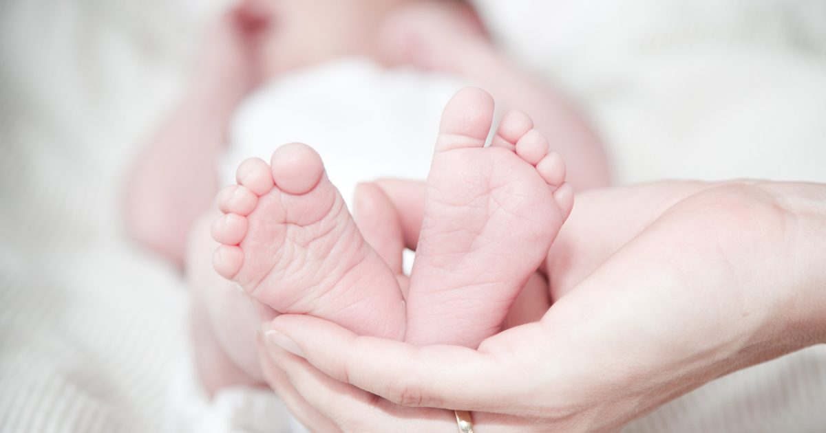 A parent holding a newborn baby's feet