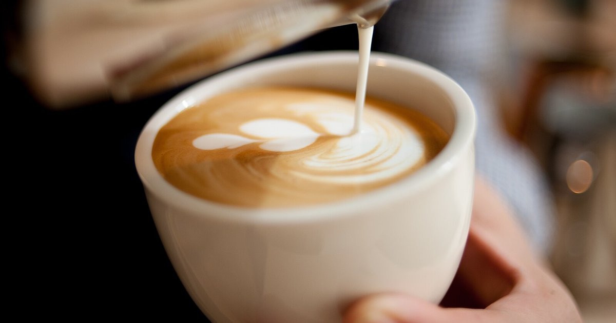 A barista pouring steamed milk into a latte