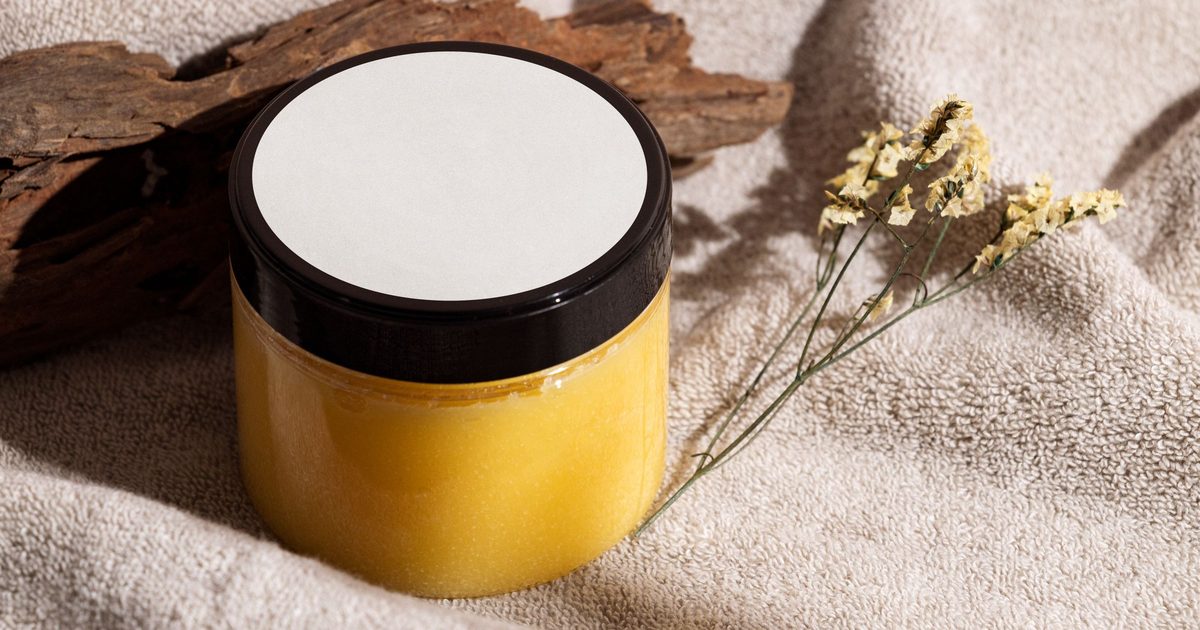 A jar of amber tallow balm on a folded towel with dried flowers
